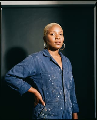 Studio portrait of a muralist in a spray-paint-stained boilersuit.