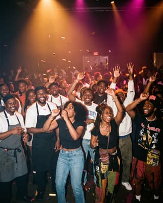 A joyful crowd of artists, chefs and students dancing under warm light.